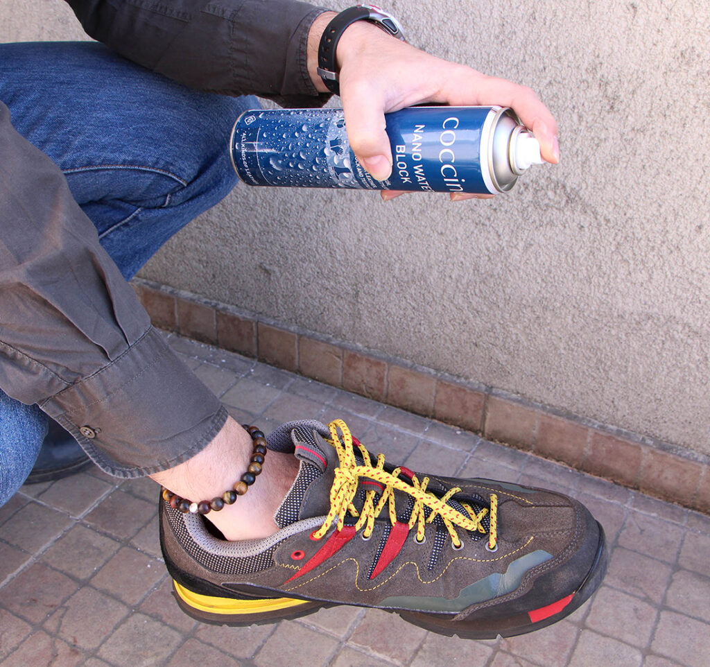 Dłoń pryskająca obuwie impregnatem do butów trekkingowych